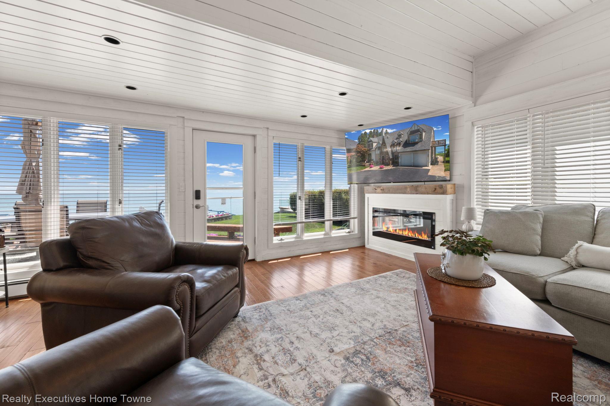 8308 Lakeshore Road Fort Gratiot, MI 48059 - Photo 50 of 79 Living area featuring white paneled walls and ceiling, hardwood flooring, and a modern linear fireplace with a reclaimed wood mantel