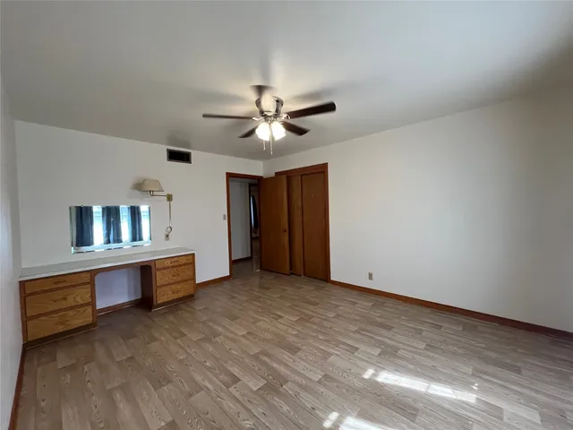a view of an empty room with window and chandelier fan