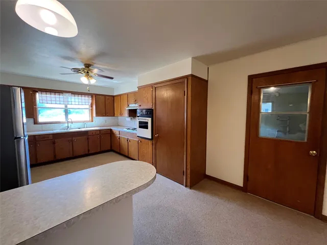 a kitchen with stainless steel appliances a refrigerator a sink dishwasher with a dining table and chairs