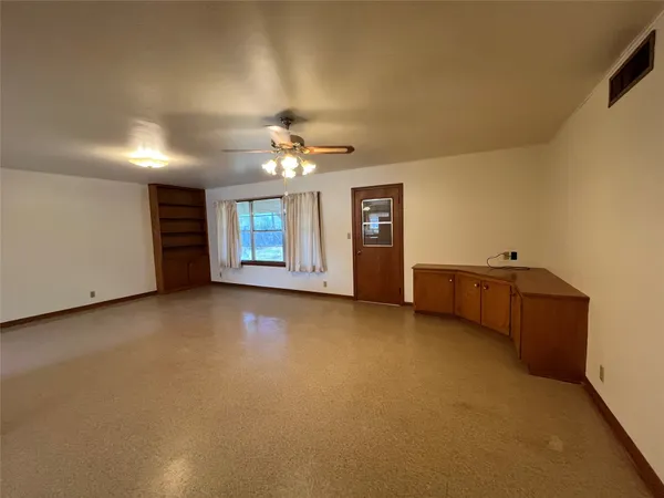 a view of an empty room with a chandelier fan