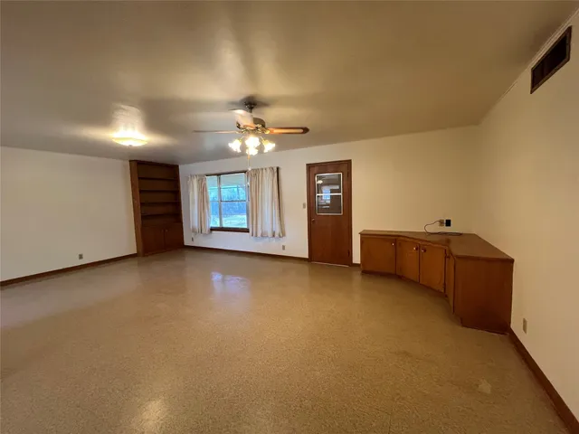 a view of an empty room with a chandelier fan