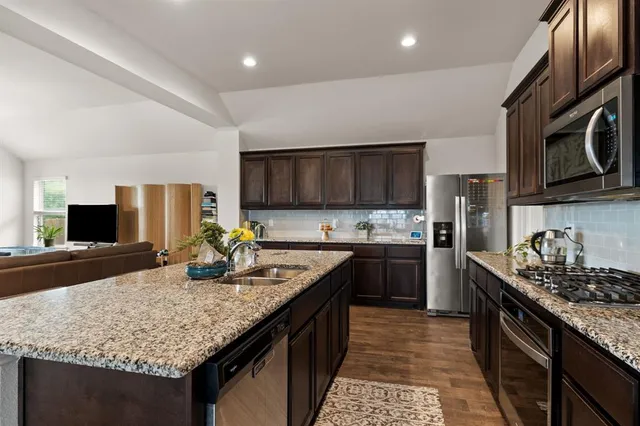 a kitchen with stainless steel appliances granite countertop a sink stove and microwave