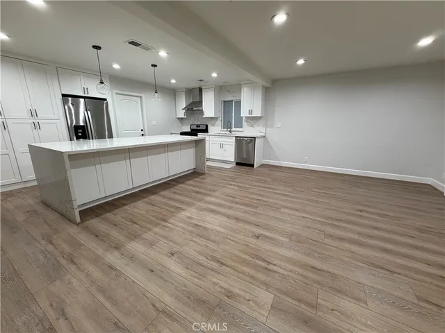 a large kitchen with stainless steel appliances granite countertop a large counter top and white cabinets