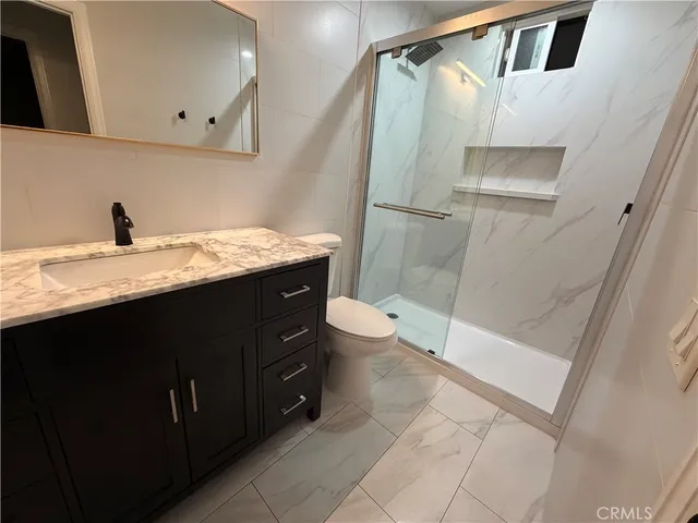 a bathroom with a granite countertop sink toilet and shower