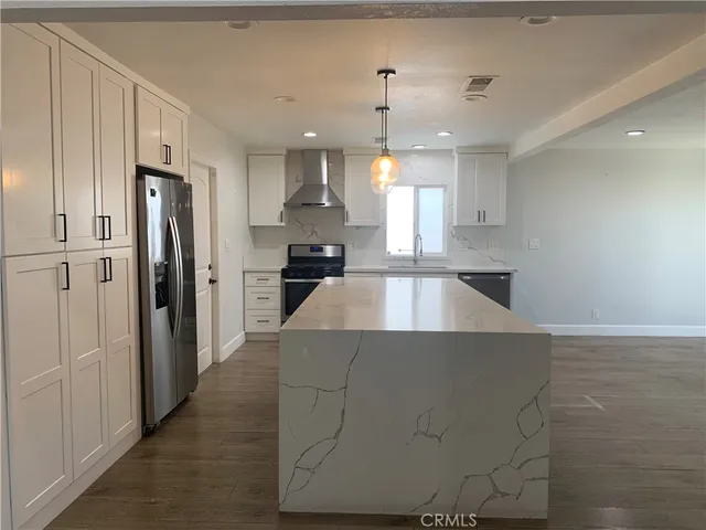 a large kitchen with a refrigerator a sink dishwasher a oven with white cabinets and wooden floor