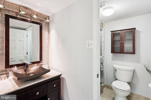 a bathroom with a granite countertop sink and a toilet