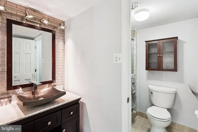 a bathroom with a granite countertop sink and a toilet