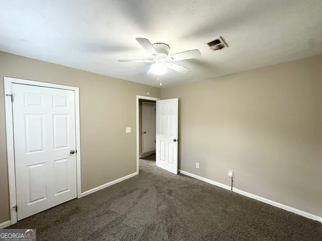 an empty room with closet and a ceiling fan