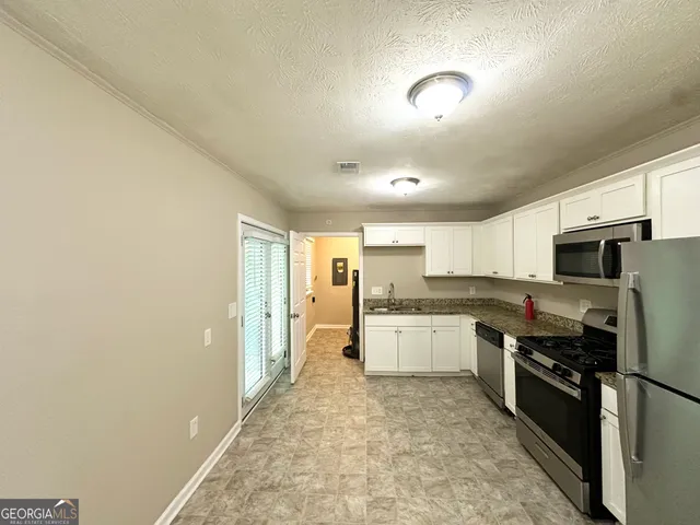 a large kitchen with stainless steel appliances lots of counter space and wooden floor