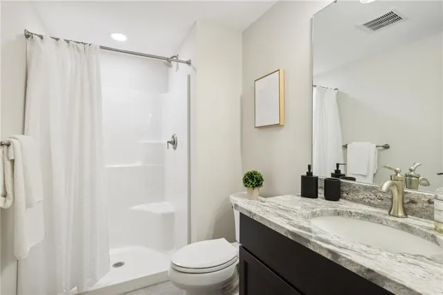 a bathroom with a granite countertop sink toilet and shower
