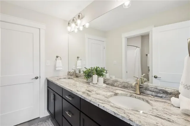 a bathroom with a granite countertop double vanity sink and a mirror