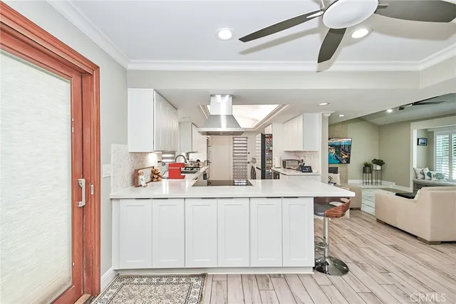 a kitchen with stainless steel appliances a lot of white cabinets and wooden floor