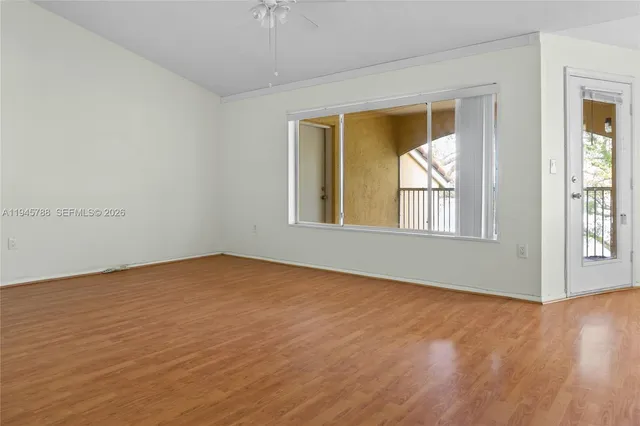 a view of an empty room with wooden floor and a window