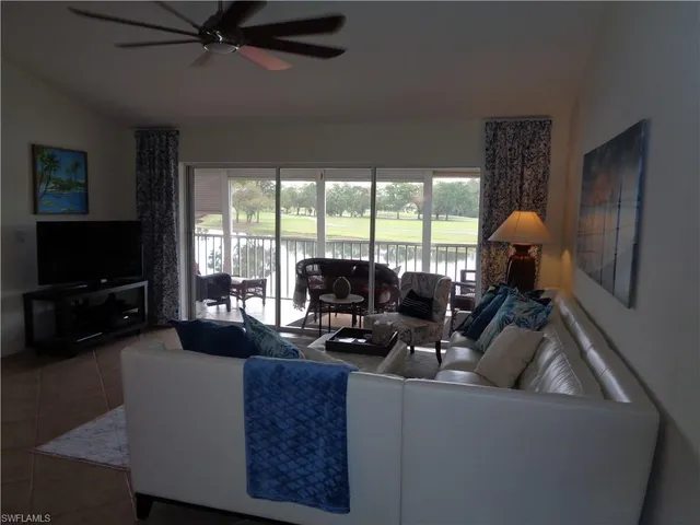 a living room with furniture a flat screen tv and a large window