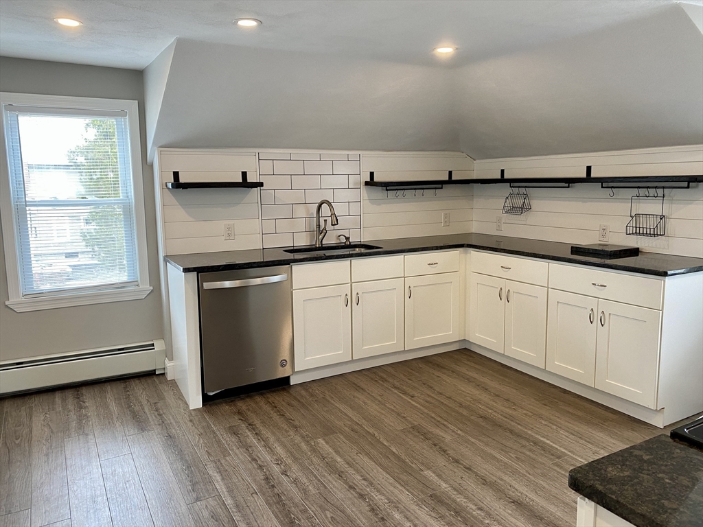 a kitchen with stainless steel appliances granite countertop a sink and cabinets with wooden floor