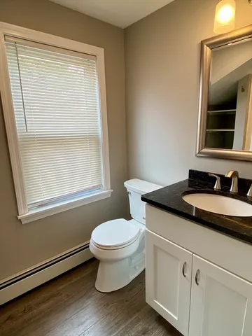 a bathroom with a granite countertop sink toilet a mirror and window