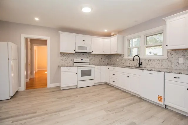 a kitchen with granite countertop white cabinets and white appliances