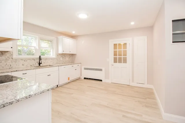a large white kitchen with granite countertop a sink window and a granite counter tops