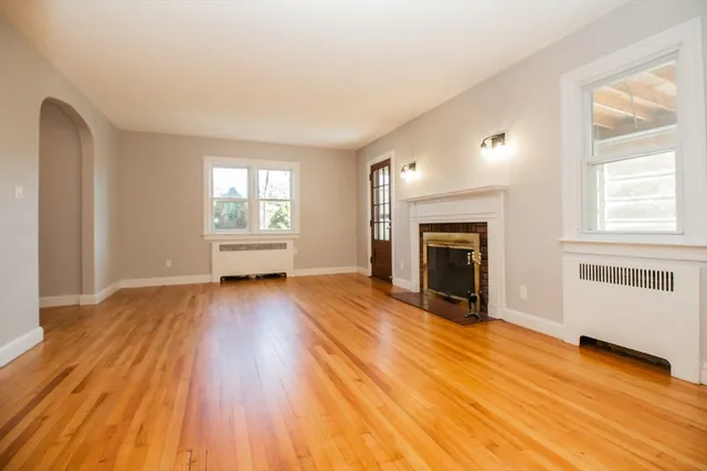 wooden floor fireplace and windows in an empty room