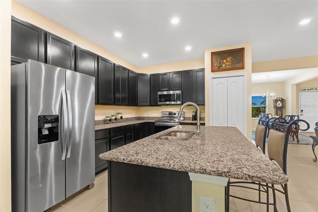 6283 Grapewood Road Spring Hill, FL 34609 - Photo 17 of 41 a kitchen with kitchen island granite countertop stainless steel appliances and a refrigerator
