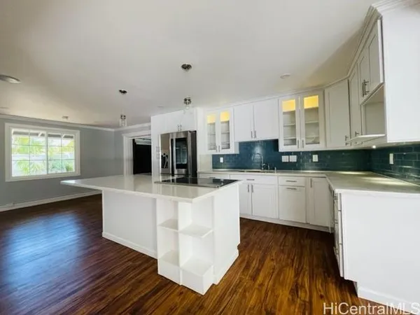 a large white kitchen with wooden floors and white stainless steel appliances