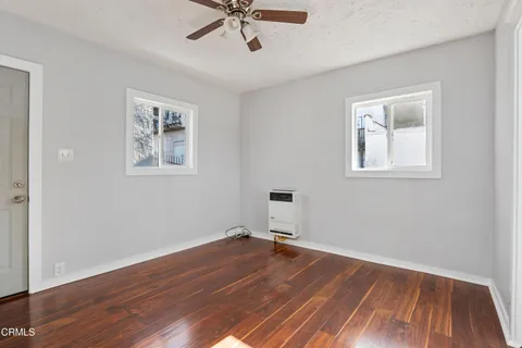 a view of empty room with wooden floor and fan