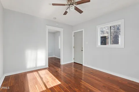 a view of empty room with wooden floor and fan