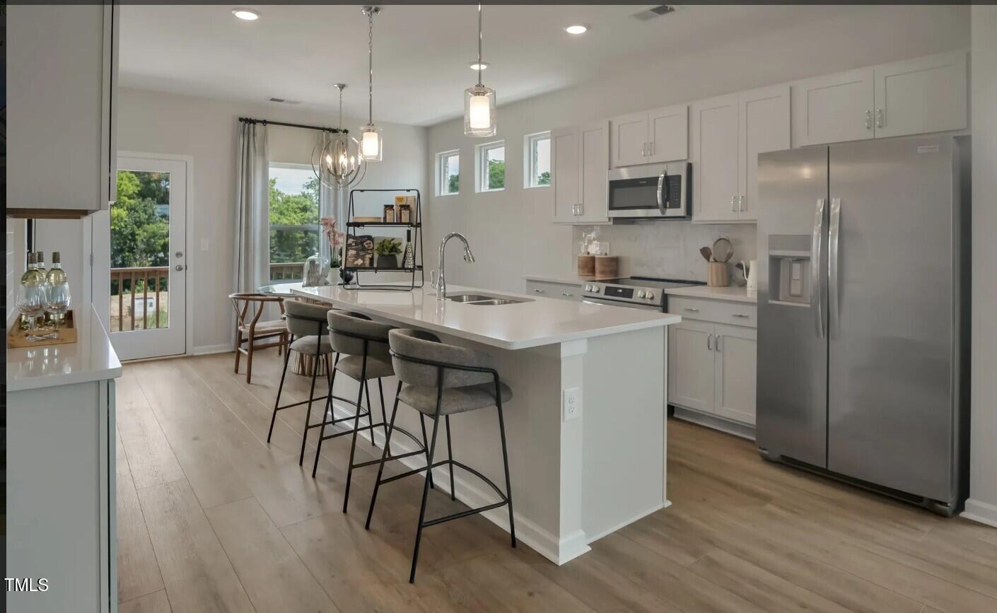 726 Orch Vista Circle Raleigh, NC 27606 - Photo 3 of 16 a kitchen with stainless steel appliances granite countertop a table chairs refrigerator and microwave