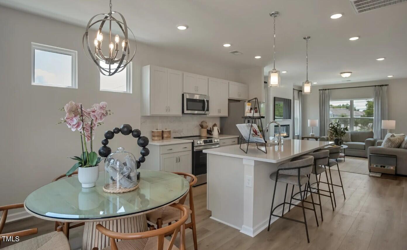 726 Orch Vista Circle Raleigh, NC 27606 - Photo 4 of 16 a view of a dining room with furniture a chandelier and wooden floor