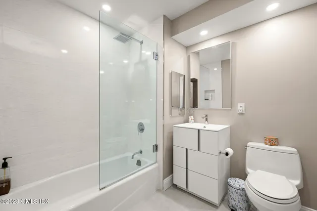 a bathroom with a bathtub shower sink mirror vanity and toilet