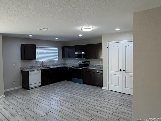 a large kitchen with stainless steel appliances granite countertop a refrigerator and a sink