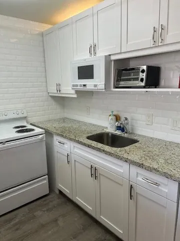 a kitchen with stainless steel appliances granite countertop white cabinets a sink and dishwasher