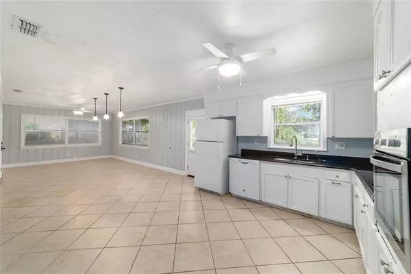 a kitchen with white cabinets a sink a window and stainless steel appliances