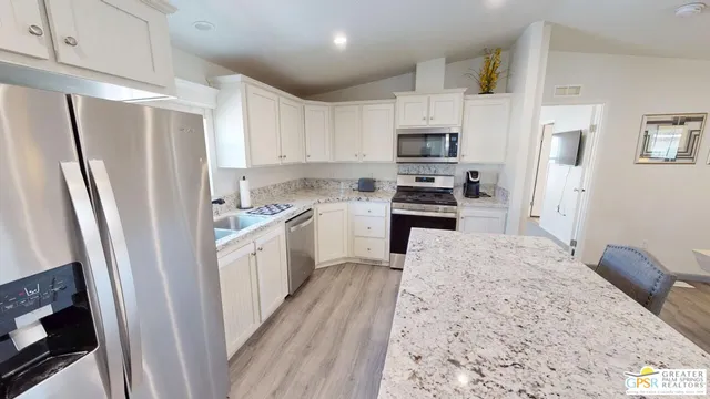 a kitchen with stainless steel appliances white cabinets and wooden floor