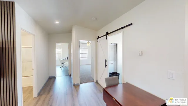 a view of a hallway with wooden floor and a bathroom