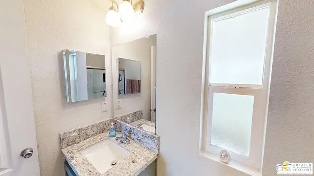 a bathroom with a granite countertop sink and a mirror