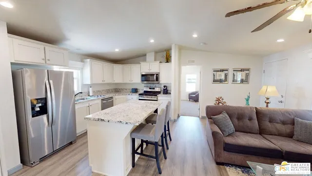 a living room with stainless steel appliances furniture and a view of kitchen