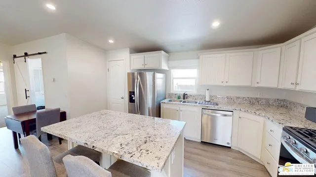 a kitchen with stainless steel appliances granite countertop a sink a stove a refrigerator with white cabinets and wooden floor