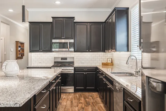 a kitchen with granite countertop a stove sink and cabinets