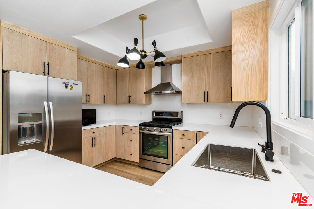 a kitchen with stainless steel appliances a stove a sink a refrigerator and a counter space
