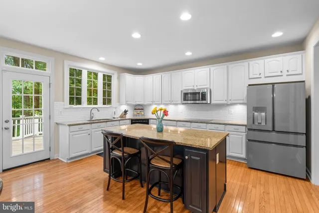a kitchen with stainless steel appliances granite countertop a table chairs sink refrigerator and microwave