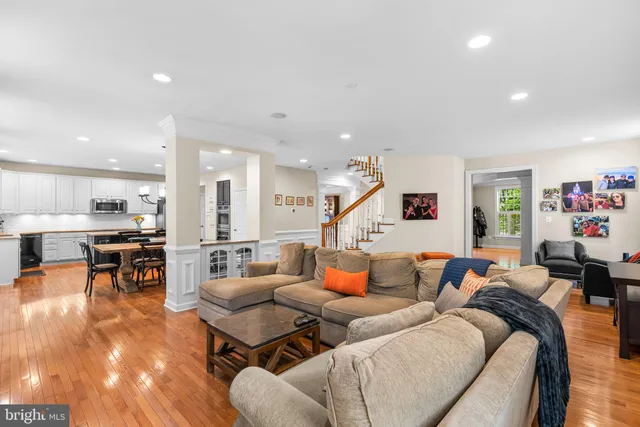 a living room with furniture kitchen view and a wooden floor