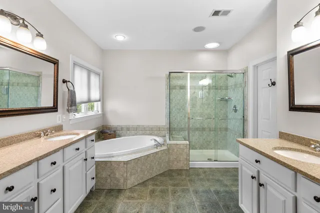 a bathroom with a double vanity sink large mirror and a bathtub