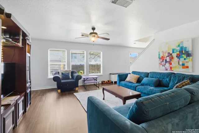 a living room with furniture ceiling fan and a flat screen tv