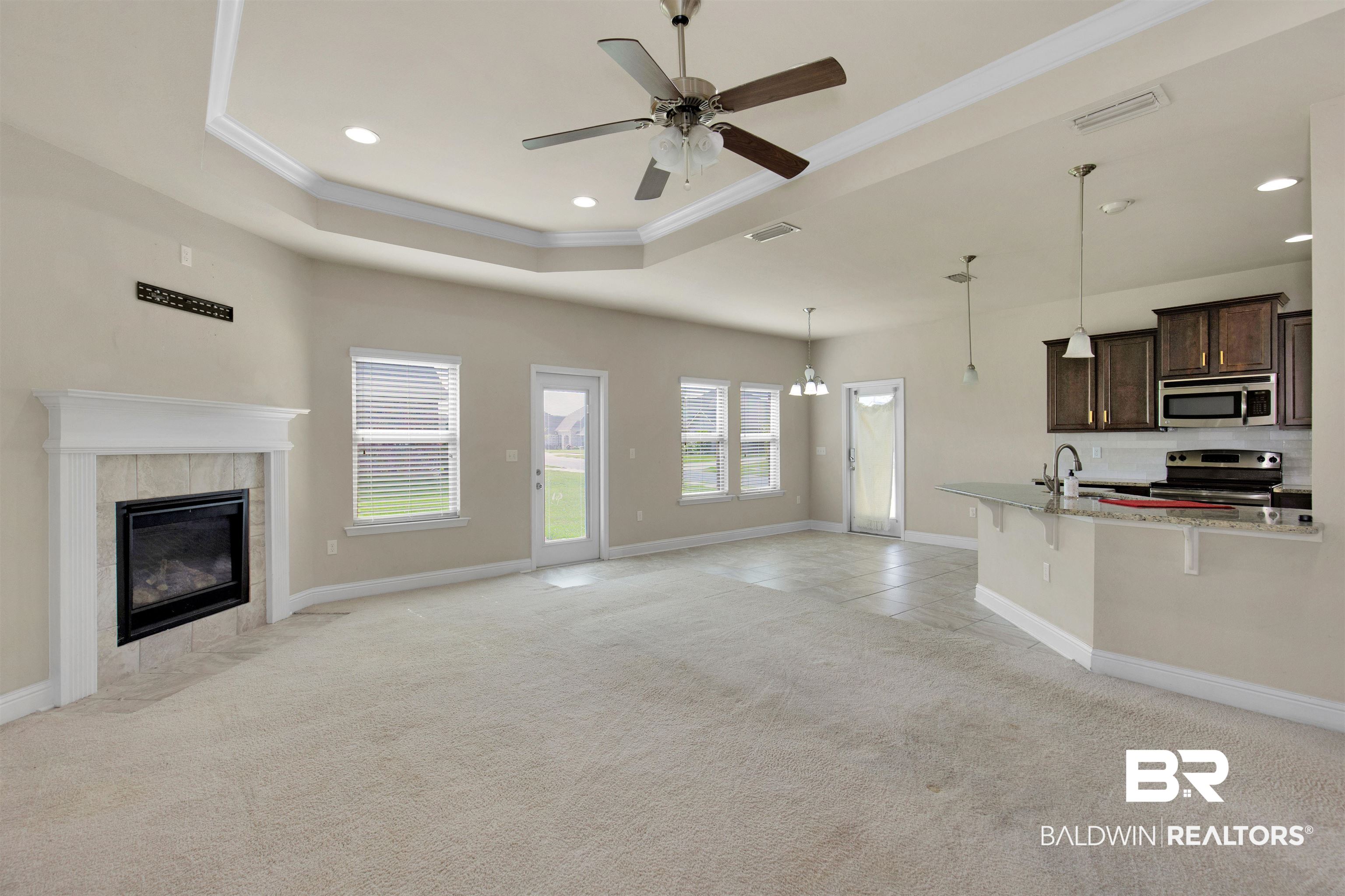 122 Open Field Drive Fairhope, AL 36532 - Photo 4 of 27 Unfurnished living room with a fireplace, ceiling fan, a raised ceiling, and light colored carpet