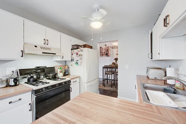 a kitchen with stainless steel appliances granite countertop a stove top oven a sink dishwasher and white cabinets with wooden floor