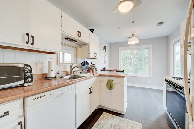 a kitchen that has a lot of cabinets and wooden floor