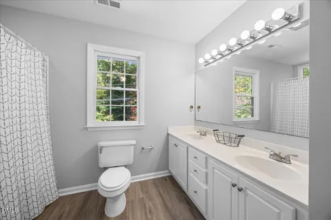 a spacious bathroom with a double vanity sink a toilet and a shower