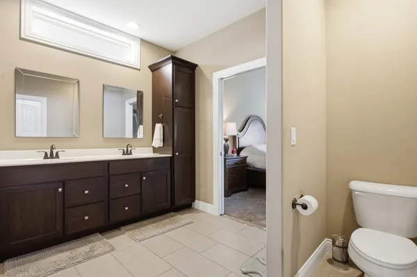a bathroom with a toilet sink vanity granite and shower