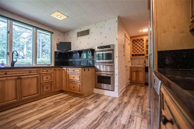 a kitchen with granite countertop a refrigerator oven a sink dishwasher and wooden cabinets with wooden floor